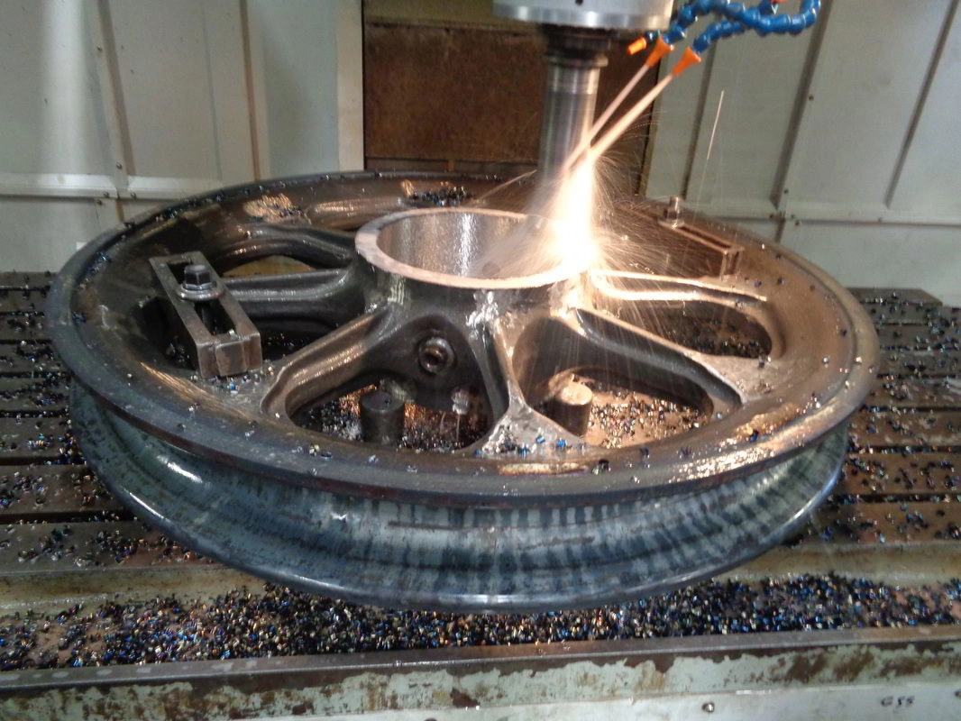 CNC machine cutting the hub of a large cast dragline sheave wheel, white-hot sparks at the tool