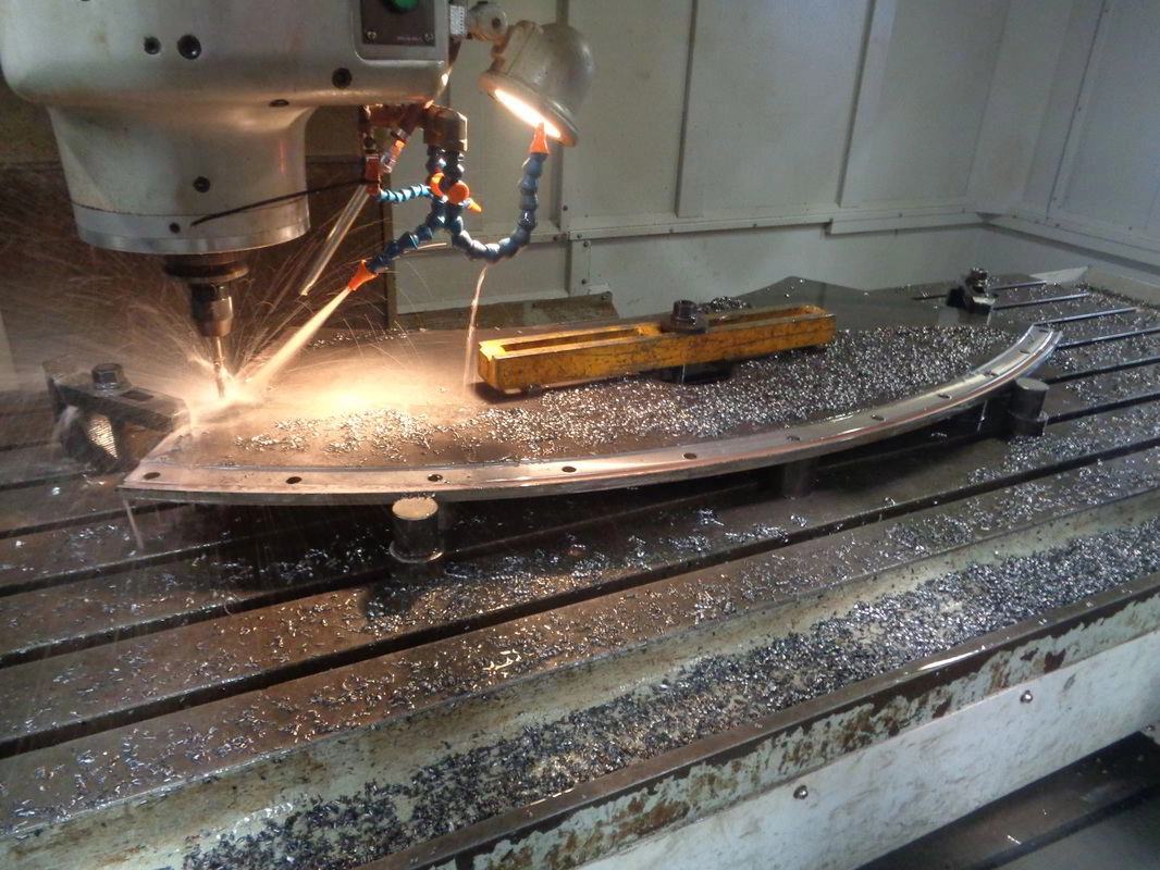 CNC floor borer machining a curved dragline boom arch section, sparks streaming