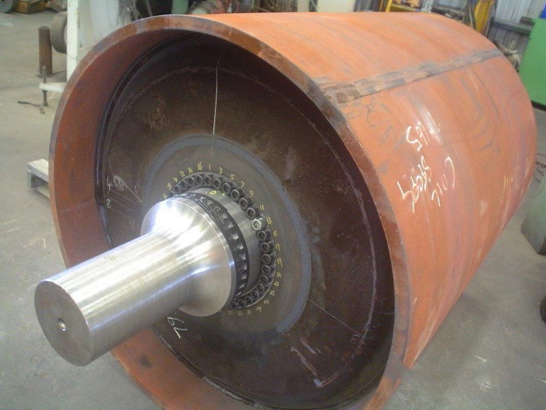 Refurbished large-diameter drum with a freshly machined shaft on stands in the workshop
