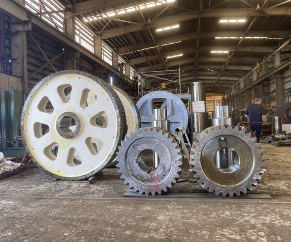 Three large fabricated gears and pinions of varying sizes standing in the ABC Heavy Engineering workshop, showing the scale of the work